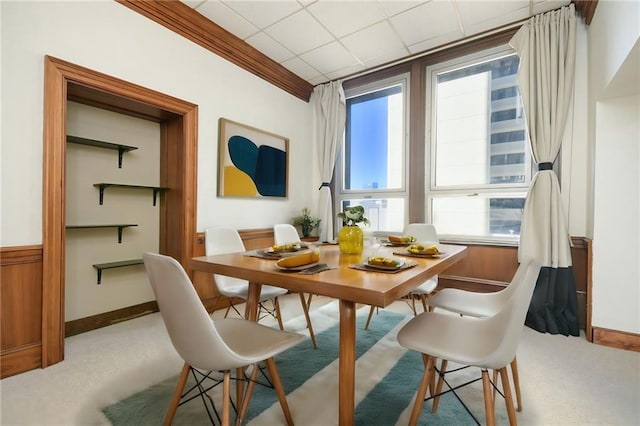 dining area featuring baseboards, ornamental molding, a drop ceiling, and light colored carpet