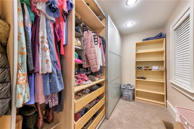 walk in closet featuring light colored carpet