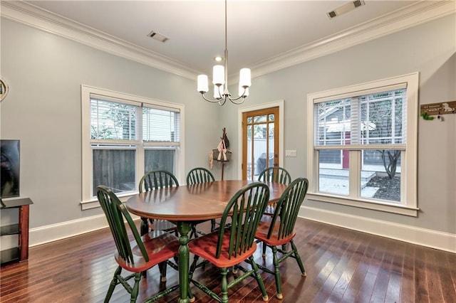 dining area with dark wood-type flooring, ornamental molding, and an inviting chandelier