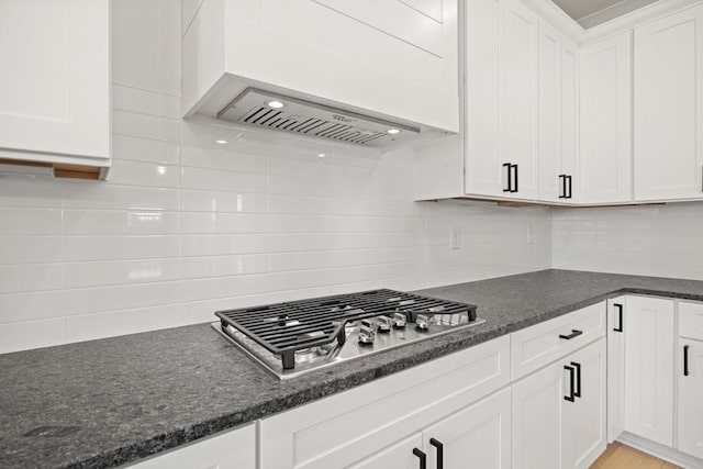 kitchen with premium range hood, stainless steel gas cooktop, white cabinets, and decorative backsplash