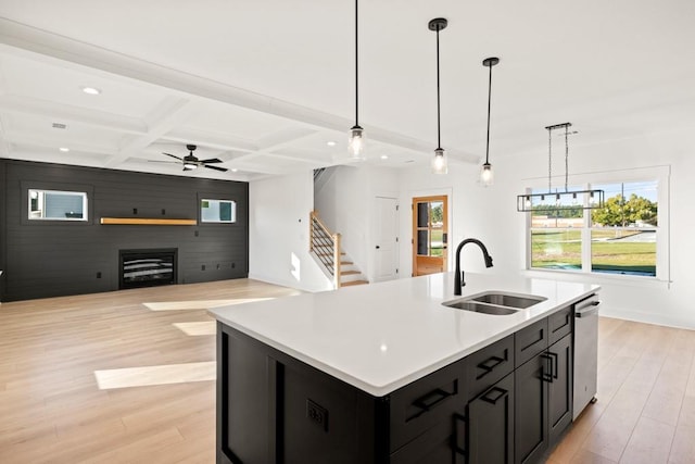 kitchen with coffered ceiling, dark cabinets, a sink, light wood-style floors, and beam ceiling