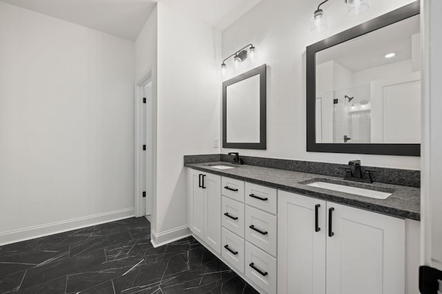 bathroom featuring marble finish floor, a sink, baseboards, and walk in shower