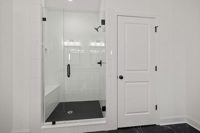 bathroom with marble finish floor, a stall shower, and baseboards