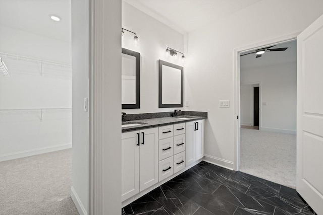 bathroom with double vanity, baseboards, a walk in closet, and a sink