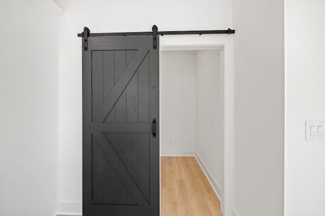 interior space featuring a barn door, wood finished floors, and baseboards