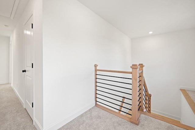 hall featuring attic access, carpet, baseboards, and an upstairs landing