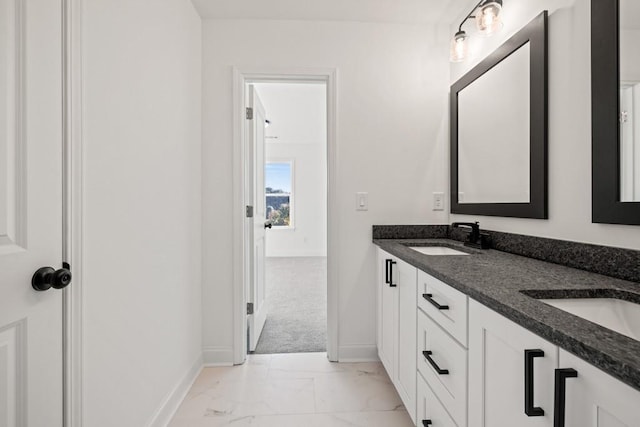 full bathroom with marble finish floor, double vanity, a sink, and baseboards