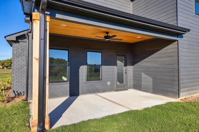 entrance to property featuring a patio area, ceiling fan, and brick siding