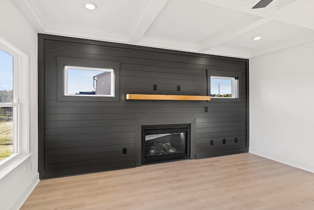 unfurnished living room featuring a large fireplace, beam ceiling, and wood finished floors