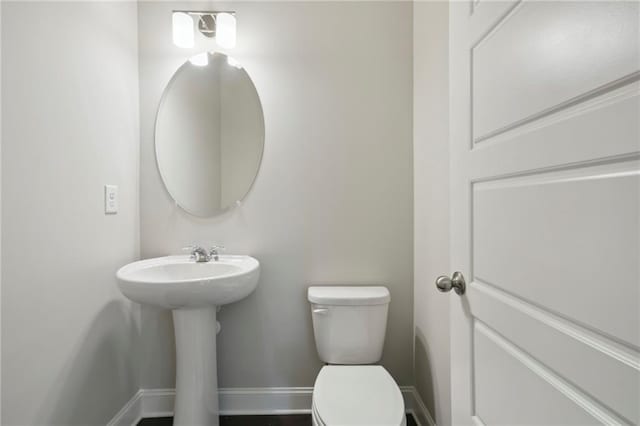 half bathroom with toilet and baseboards