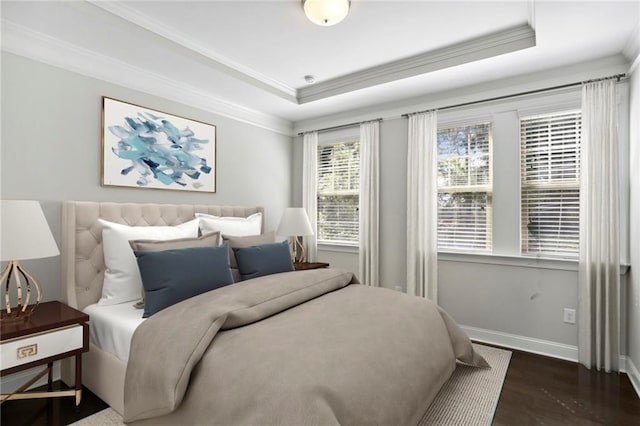 bedroom featuring baseboards, crown molding, a tray ceiling, and wood finished floors