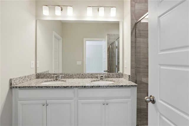 bathroom with a sink, a stall shower, and double vanity