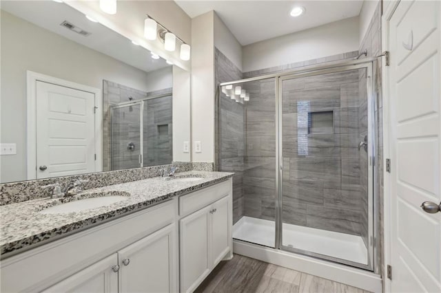 full bath with a shower stall, double vanity, visible vents, and a sink