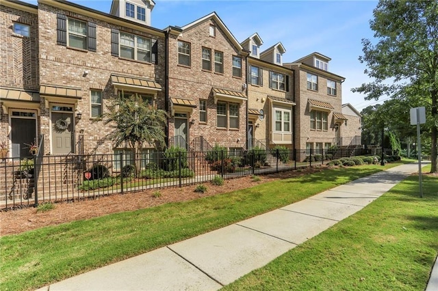 view of property featuring a fenced front yard, a residential view, and brick siding