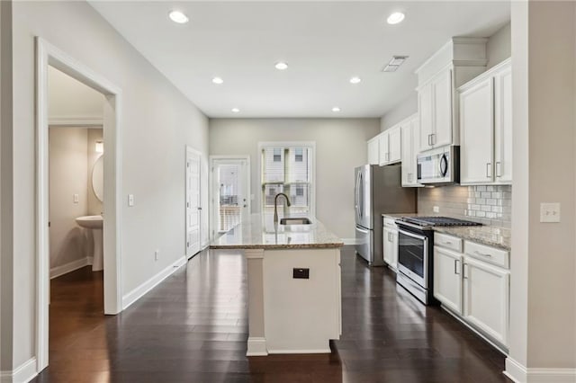 kitchen featuring dark wood-style flooring, a center island with sink, stainless steel appliances, and a sink