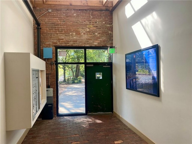 entryway with a towering ceiling, mail boxes, and brick wall