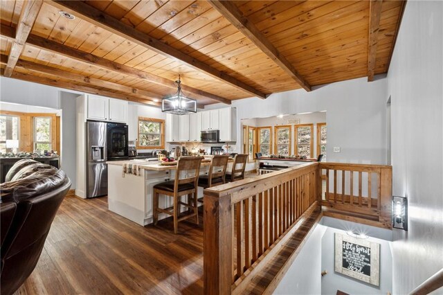 interior space with appliances with stainless steel finishes, dark hardwood / wood-style flooring, wooden ceiling, white cabinetry, and hanging light fixtures