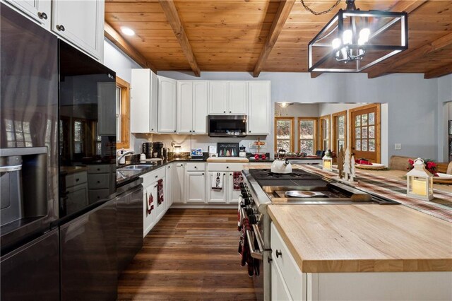 kitchen with appliances with stainless steel finishes, a notable chandelier, beam ceiling, dark hardwood / wood-style flooring, and white cabinetry