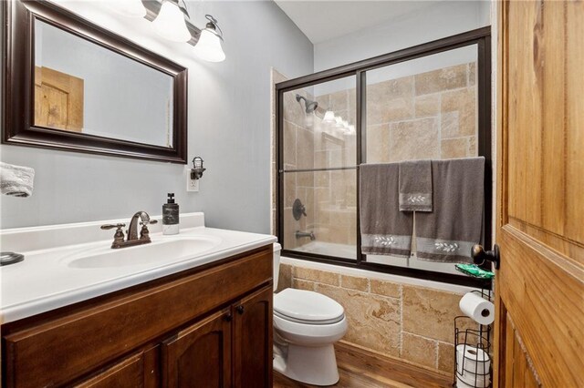 full bathroom featuring shower / bath combination with glass door, toilet, vanity, and hardwood / wood-style flooring