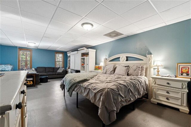 bedroom featuring concrete flooring and a paneled ceiling