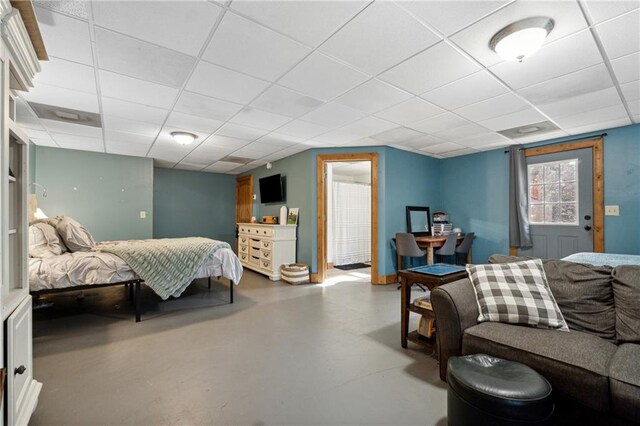 bedroom with a drop ceiling and concrete floors