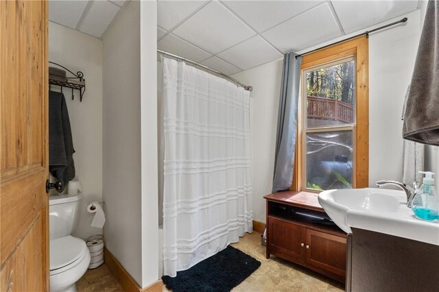 full bathroom featuring a drop ceiling, toilet, shower / bathtub combination with curtain, and vanity