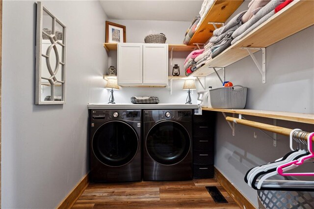 laundry room with washing machine and dryer, dark hardwood / wood-style flooring, and cabinets