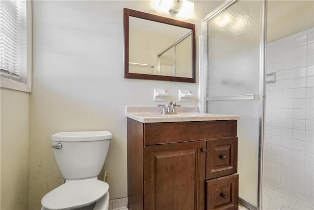 bathroom featuring vanity, toilet, and a shower with shower door