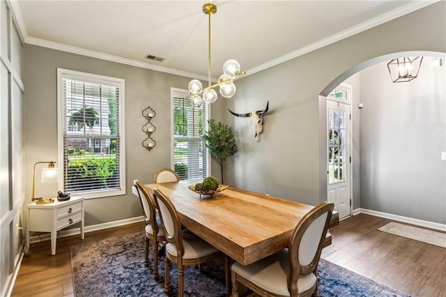 dining space with visible vents, crown molding, arched walkways, wood finished floors, and a notable chandelier