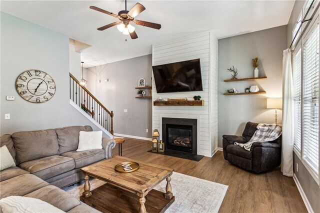 living room featuring ceiling fan, a fireplace, wood finished floors, and a wealth of natural light