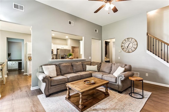 living area featuring stairs, ceiling fan, visible vents, and dark wood-style floors