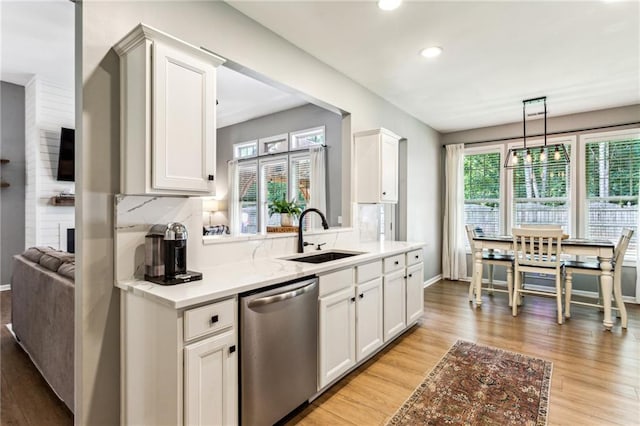 kitchen with a sink, baseboards, stainless steel dishwasher, and light wood-type flooring