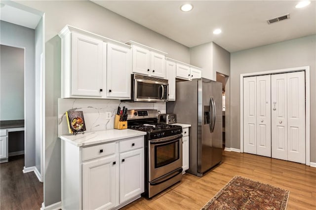 kitchen with white cabinetry, appliances with stainless steel finishes, light wood finished floors, and visible vents
