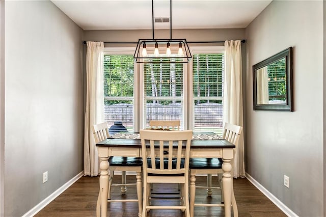 dining area with dark wood-style flooring, baseboards, visible vents, and a chandelier