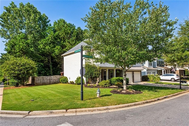 mid-century inspired home featuring concrete driveway, fence, and a front yard