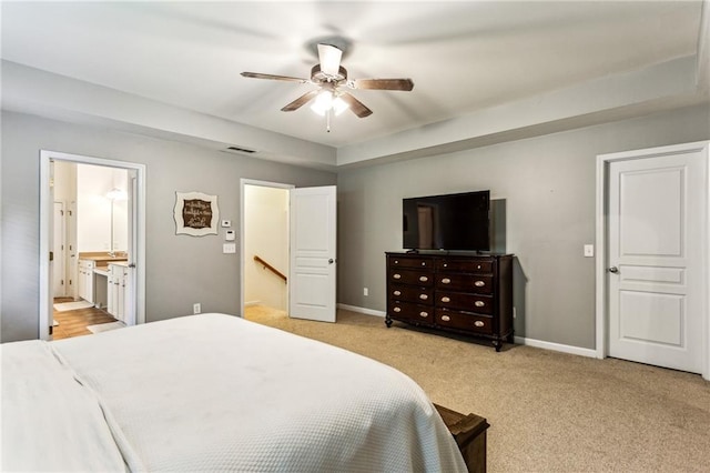 bedroom featuring connected bathroom, baseboards, light colored carpet, and ceiling fan