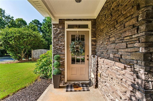 doorway to property with a yard and stone siding