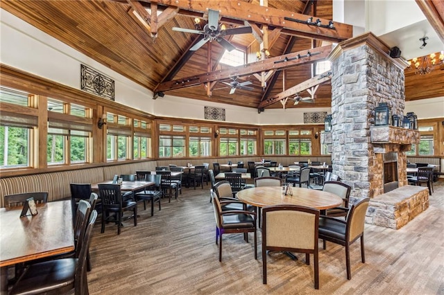 dining room featuring a fireplace, high vaulted ceiling, ornate columns, wood ceiling, and a ceiling fan