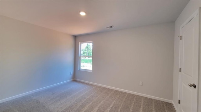 empty room featuring light colored carpet, baseboards, and visible vents