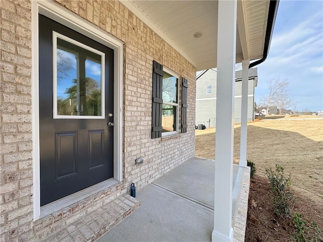 entrance to property featuring brick siding and covered porch