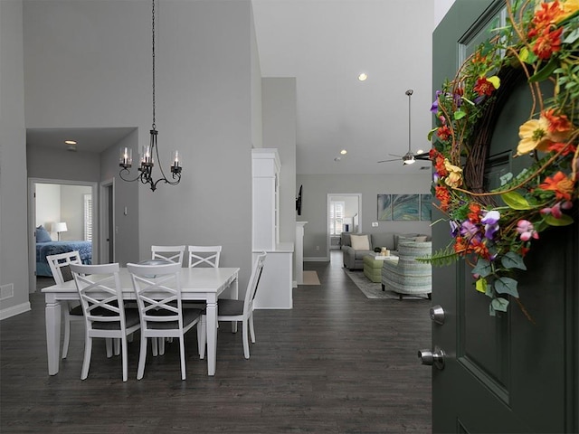 dining area with a high ceiling, ceiling fan with notable chandelier, and dark hardwood / wood-style flooring