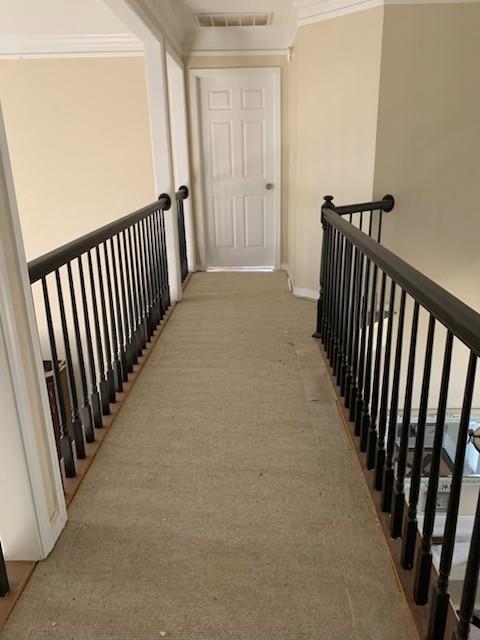hallway with light colored carpet, crown molding, an upstairs landing, and baseboards