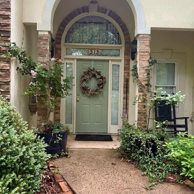 view of exterior entry featuring stucco siding and stone siding