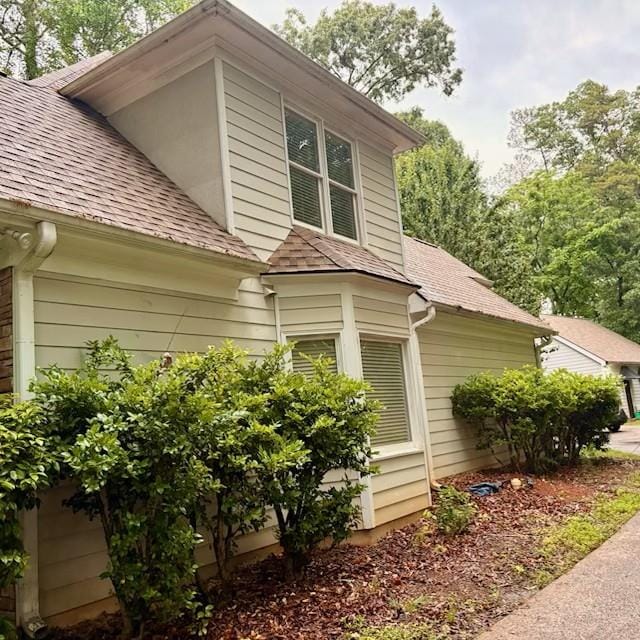 view of property exterior with a shingled roof
