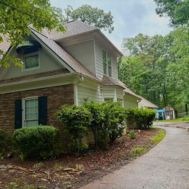 view of home's exterior with a shingled roof and stone siding