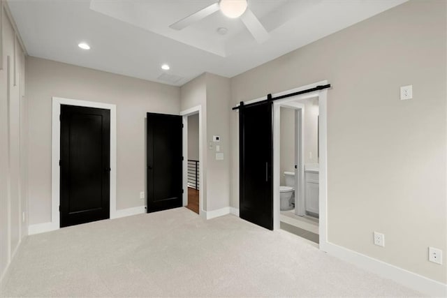 unfurnished bedroom with a barn door, connected bathroom, carpet, baseboards, and recessed lighting