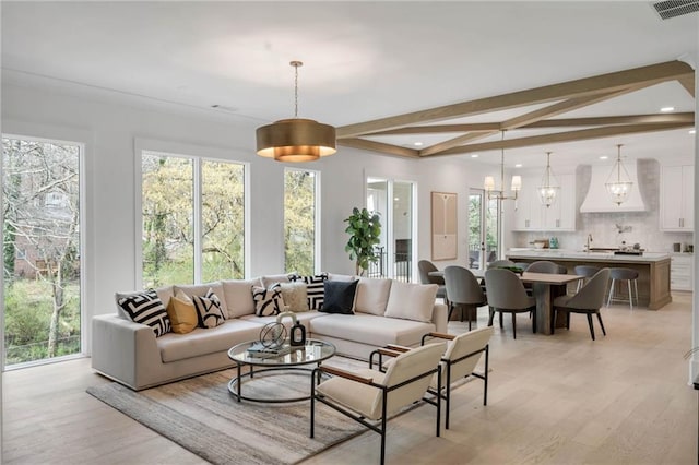 living room featuring a chandelier, light hardwood / wood-style flooring, sink, and beamed ceiling