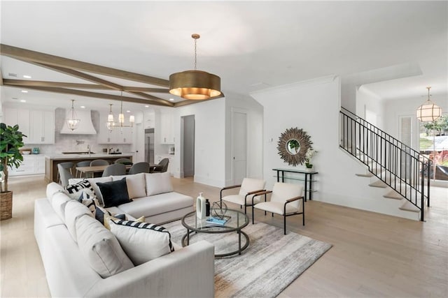 living room featuring beamed ceiling, an inviting chandelier, and light hardwood / wood-style floors