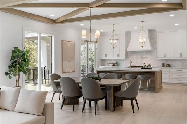 dining area featuring light wood-type flooring, an inviting chandelier, beam ceiling, and sink