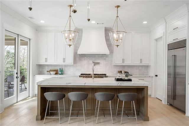 kitchen featuring stainless steel built in fridge, a large island, french doors, and custom exhaust hood